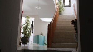 A staircase with wooden railings and a potted plant on the landing. - Michaela (Kefalonia)