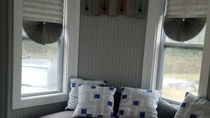 A bedroom with a built-in bench along the window, a bed with a white and blue patterned bedspread, and a ceiling with a decorative panel.