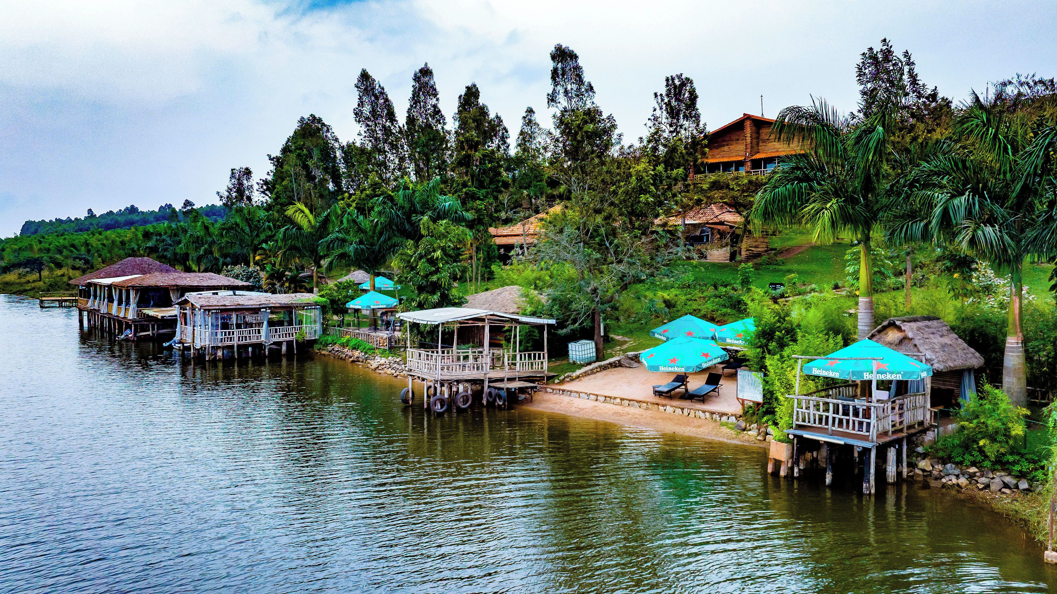 A riverside accommodation with floating structures, outdoor seating, and a view of the surrounding greenery.