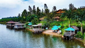 A riverside accommodation with floating structures, outdoor seating, and a view of the surrounding greenery. - Vintage Cottage (Gishari)