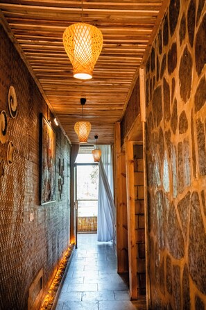 A corridor with wooden slats on the ceiling, stone walls, and hanging paper lanterns. - Vintage Cottage (Gishari)