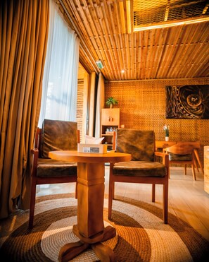 A room with a wooden ceiling, a round table, two chairs, a sofa, and a patterned rug. - Vintage Cottage (Gishari)