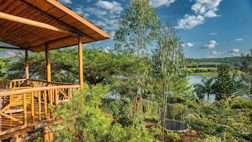 Terraza de madera con vista a un lago y vegetación circundante.