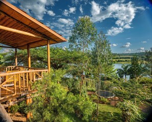 A wooden deck with a view of a lake and surrounding greenery. - Vintage Cottage (Gishari)