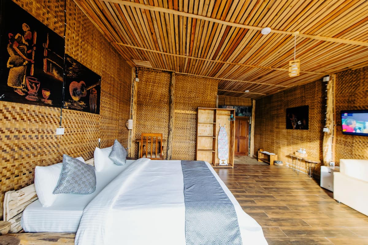 Ein Zimmer mit einem großen Bett, Holzboden und einem Fernseher an der Wand.