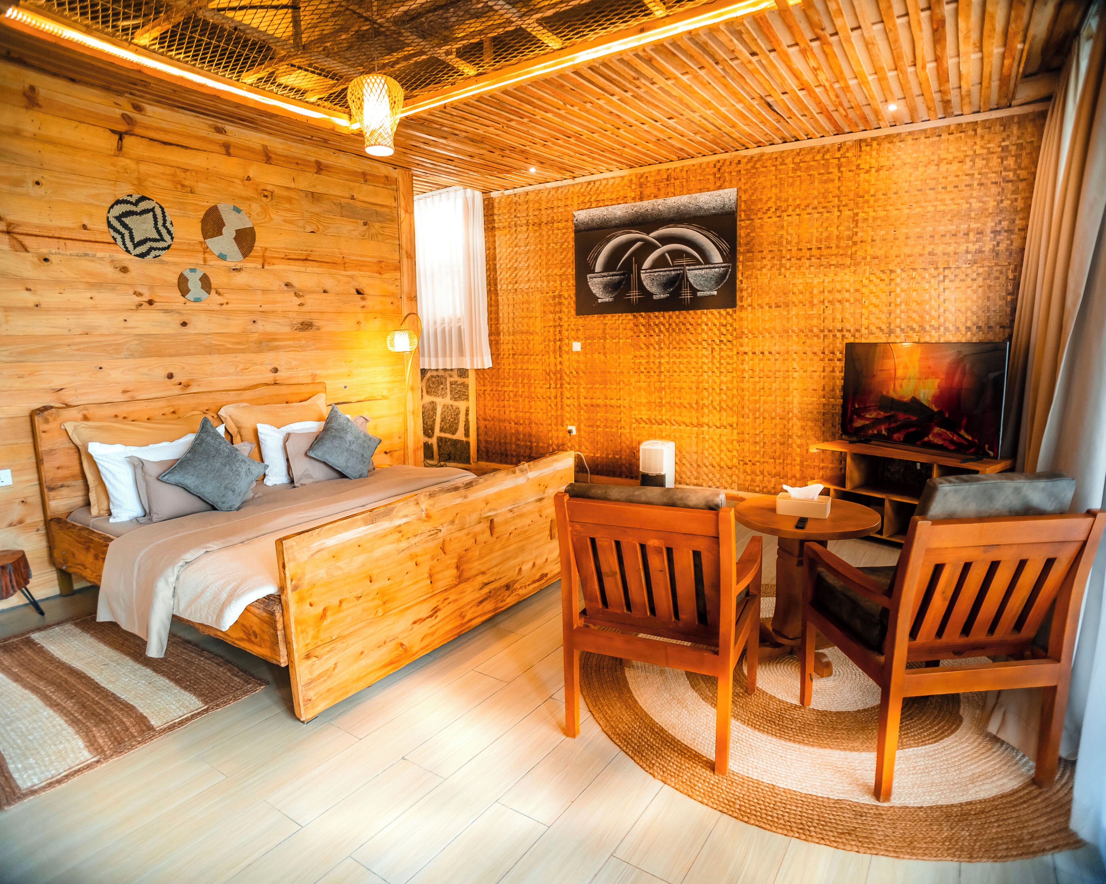 A cozy wooden room with a bed, a small table, and a TV.