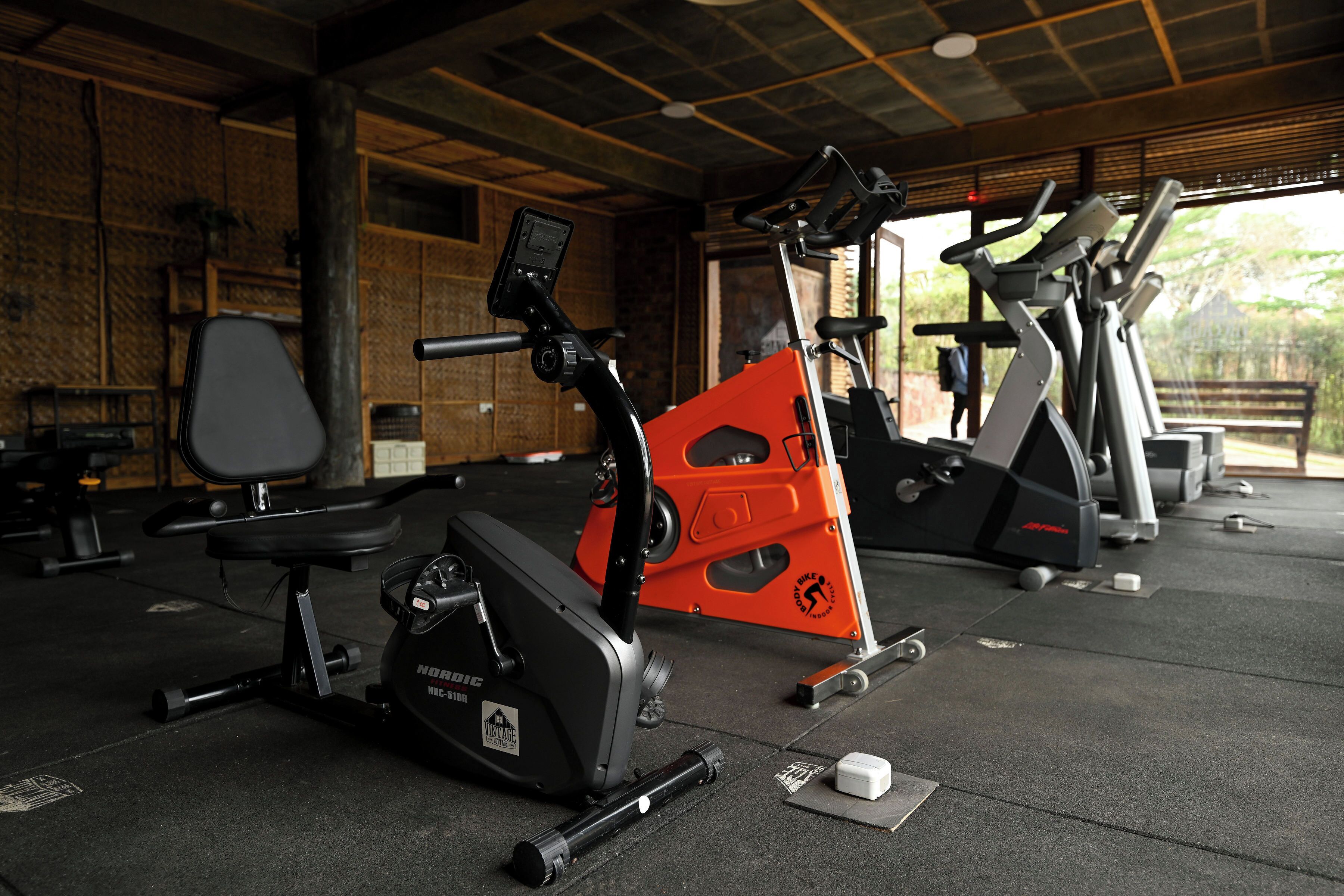 A gym with stationary bikes and treadmills, wooden walls, and a concrete floor.