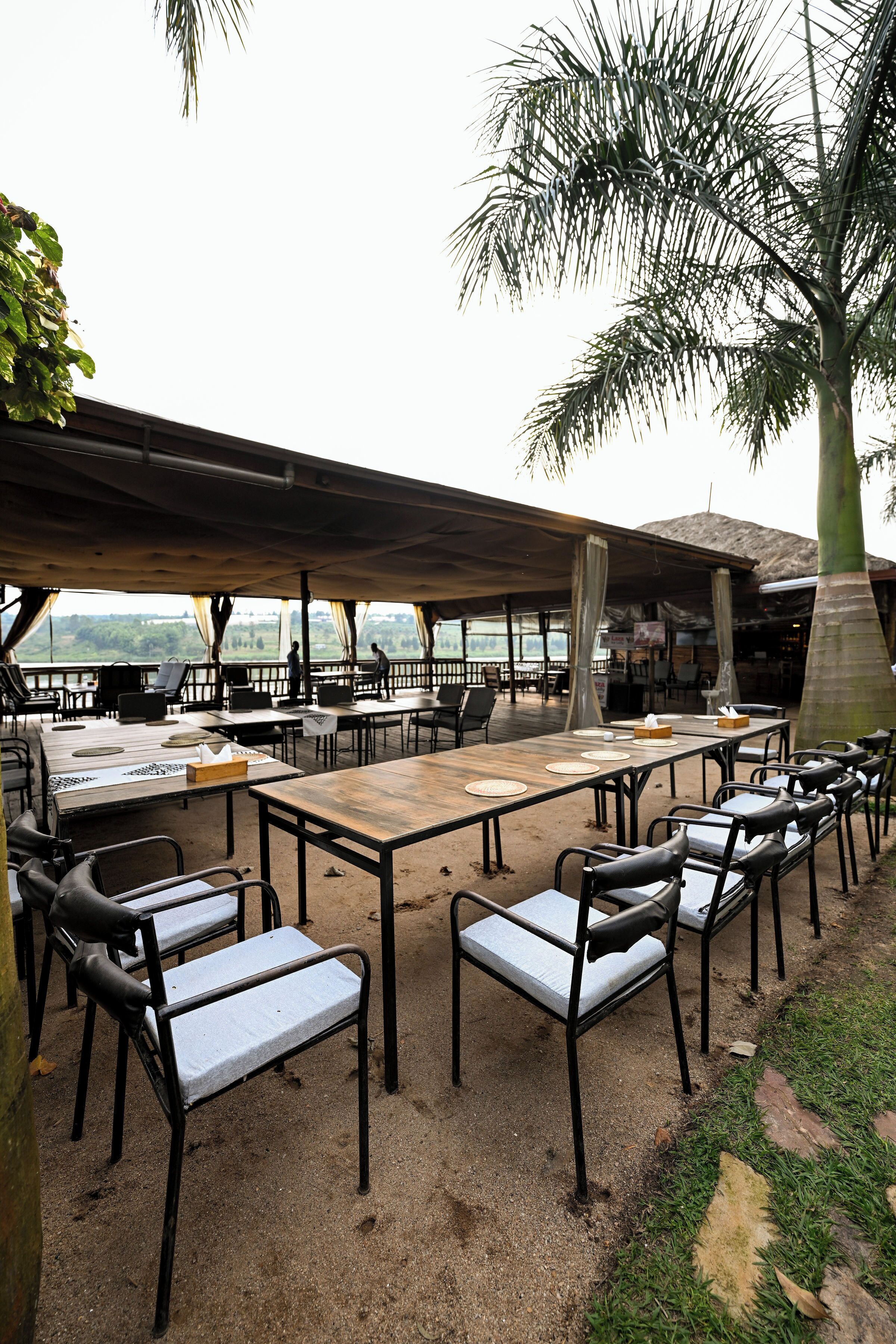 An outdoor dining area with tables and chairs, a covered seating area, and a view of the landscape.
