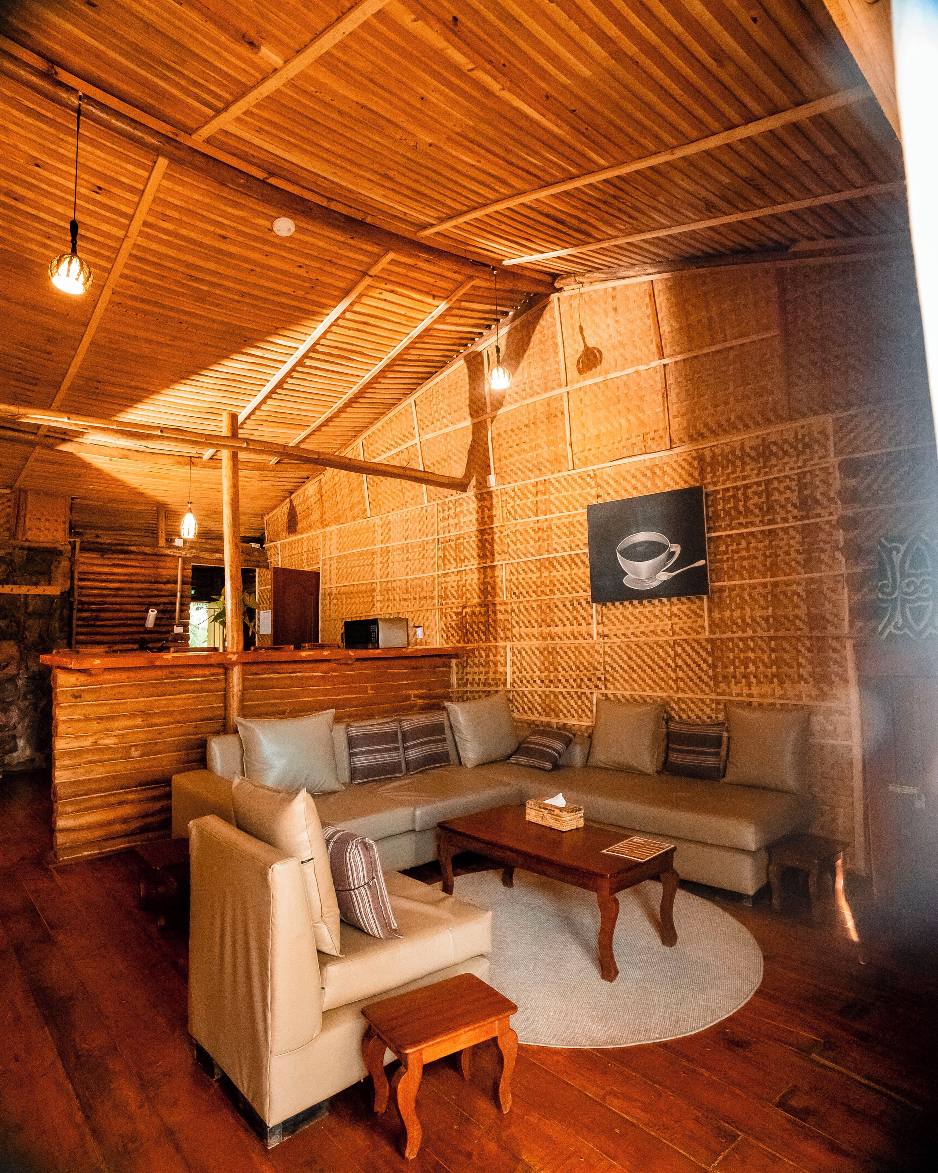 A cozy living room with a wooden ceiling, a sofa set, a coffee table, and a framed picture on the wall.