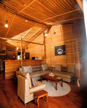 A cozy living room with a wooden ceiling, a sofa set, a coffee table, and a framed picture on the wall. - Vintage Cottage (Gishari)
