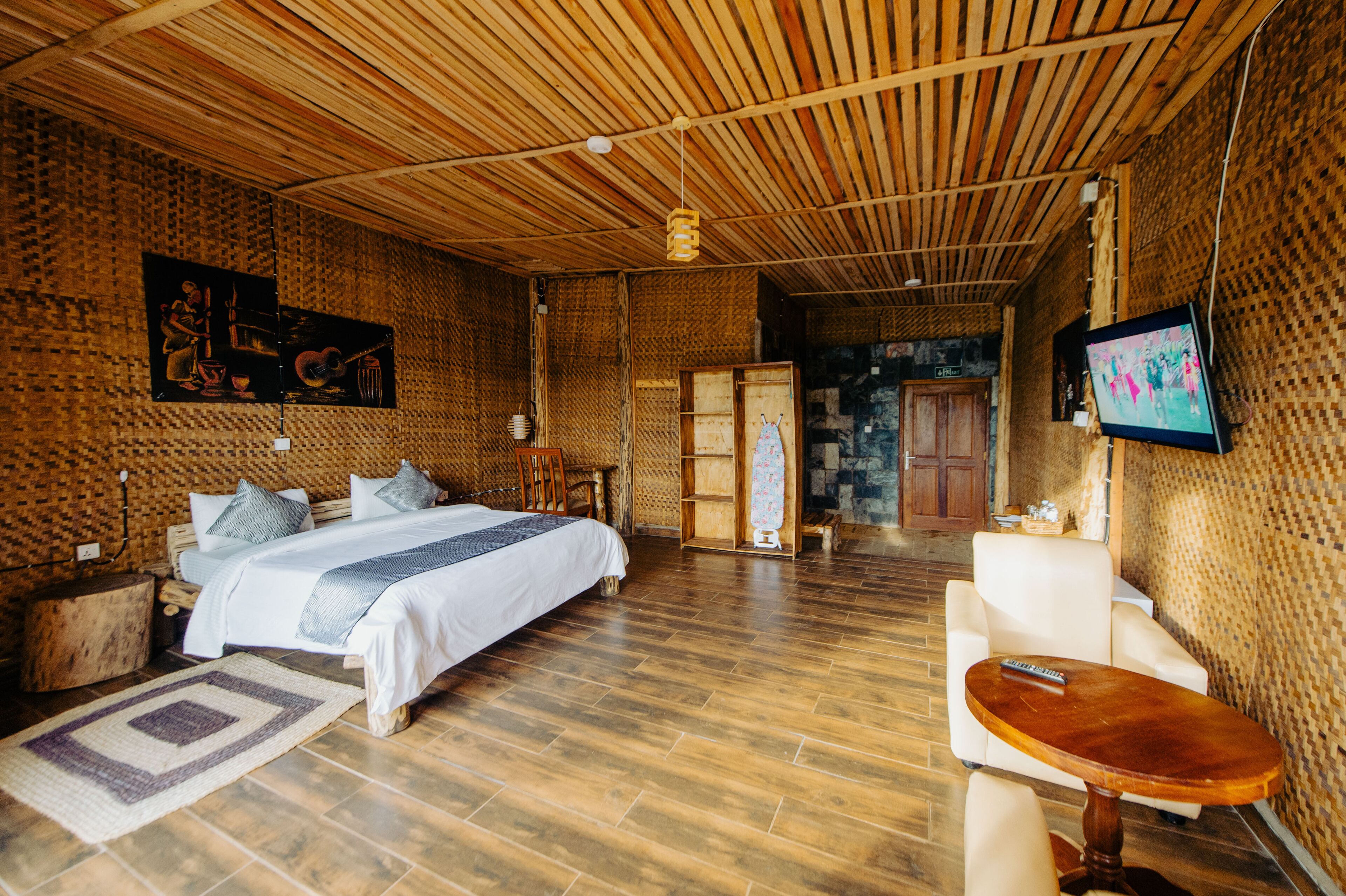 A spacious hotel room with a large bed, a wooden ceiling, and a TV on the wall.