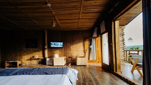 A room with a bed, a TV, a small table, and a chair. There is a balcony with a view of the landscape. - Vintage Cottage (Gishari)