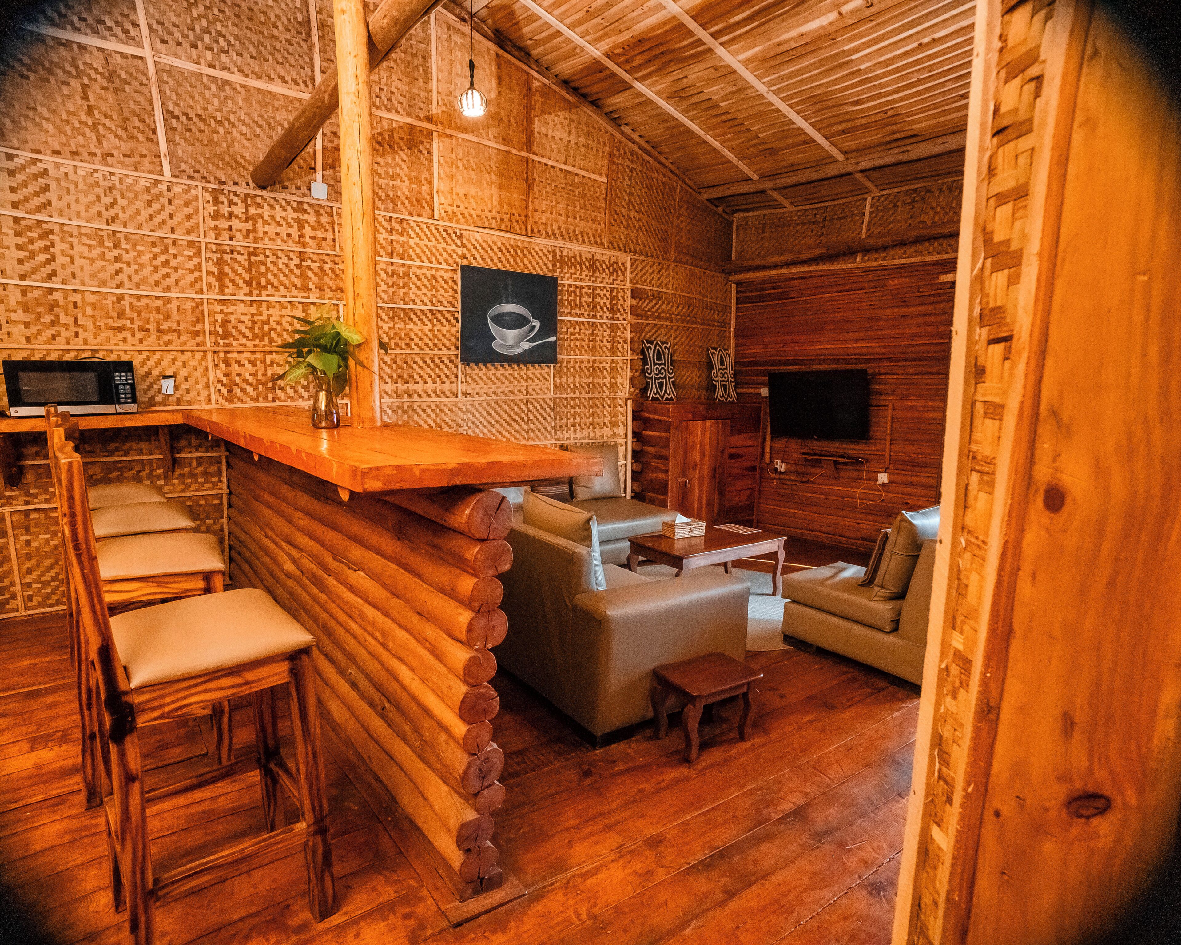 A cozy log cabin interior with a bar area, seating, and a television.