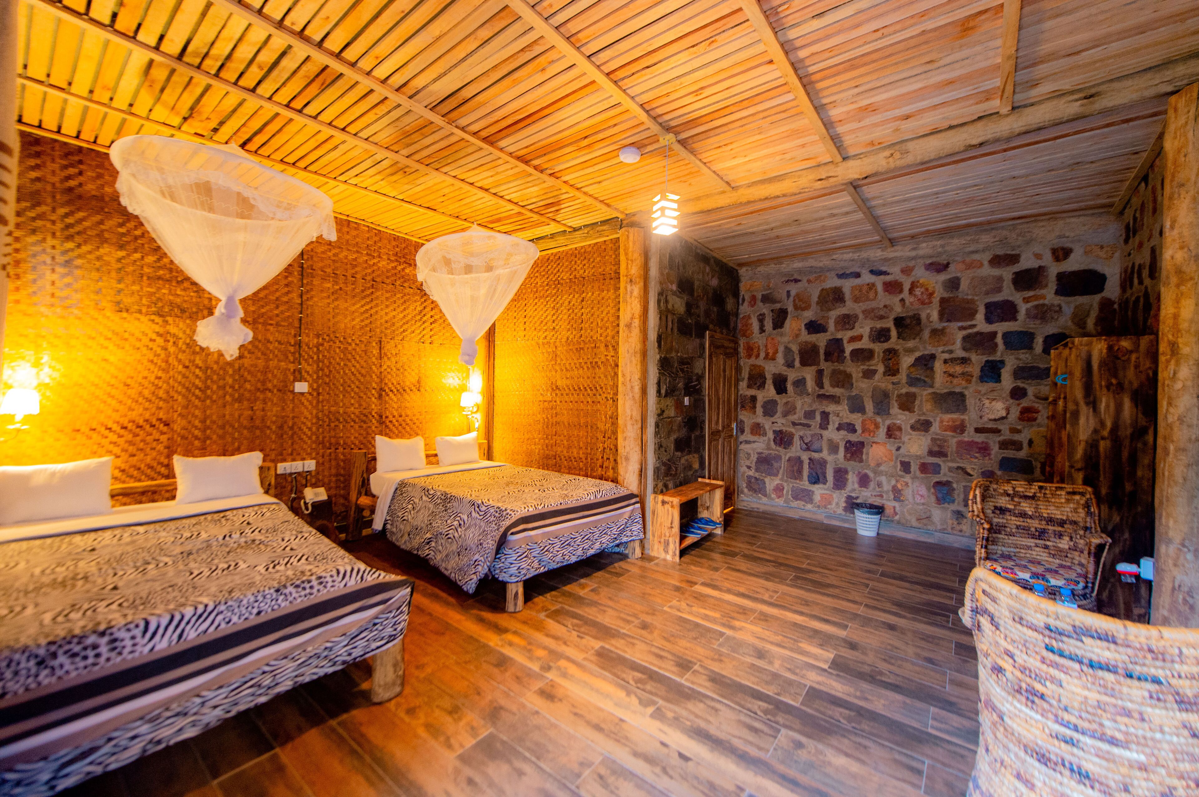 A cozy room with two beds, a stone wall, and a wooden ceiling.