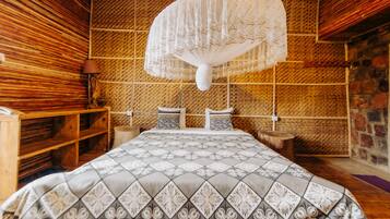A room with a bed, wooden shelves, a woven wall, and a hanging light fixture.
