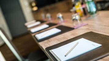 Ein Konferenztisch mit Notizbuch, Stift und einer Wasserflasche im Hintergrund.