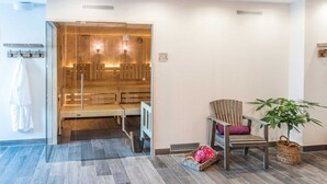 Un moderno cuarto de spa con sauna de madera, una silla de relajación y una planta en maceta.