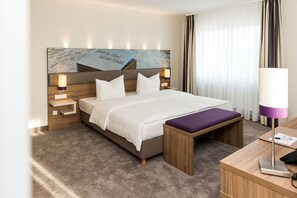 A hotel room with a large bed, a wooden bench, a desk, and a nightstand. - Stratmanns Hotel (Lohne)