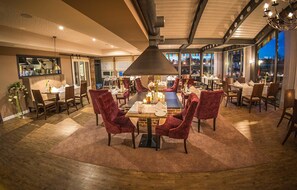 A dining area with a large table, red upholstered chairs, and a modern chandelier. - Stratmanns Hotel (Lohne)