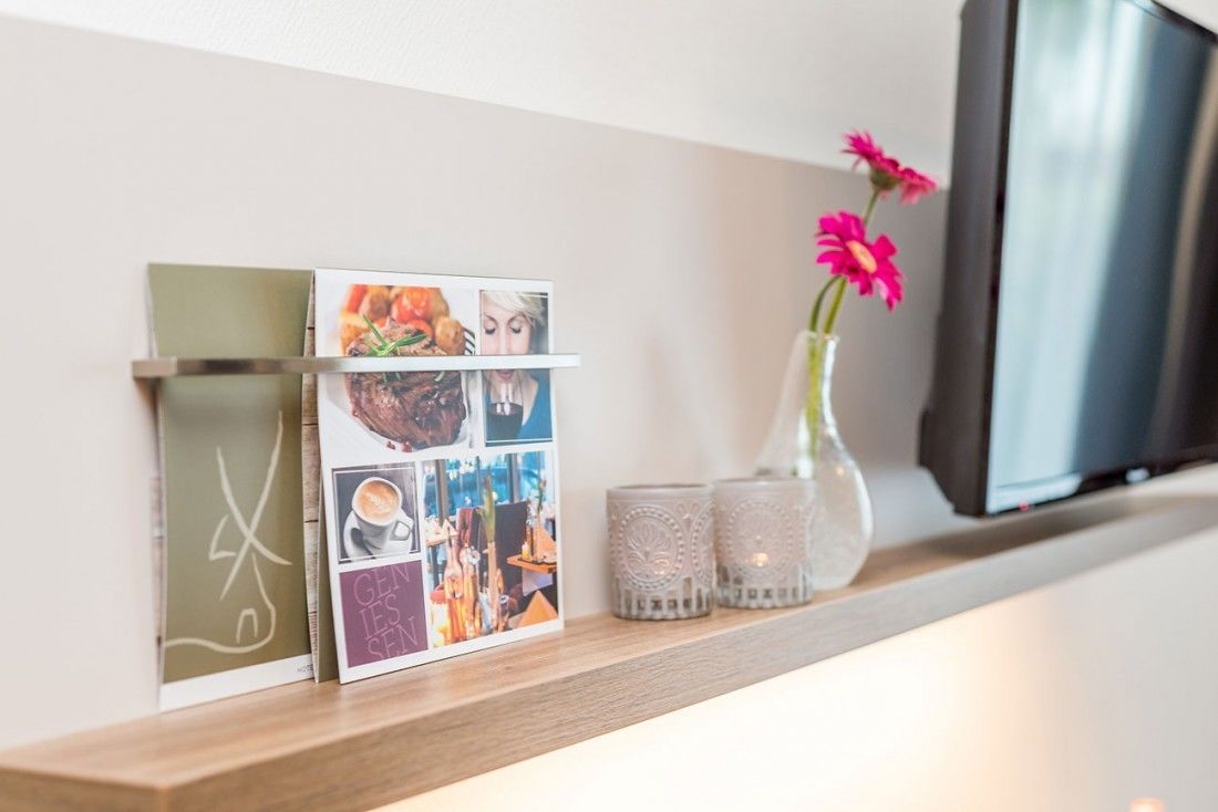 Una estantería con marcos de fotos, un jarrón con flores y un televisor.