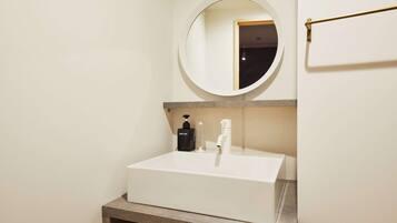 A bathroom with a white sink, a round mirror, and a towel rack.