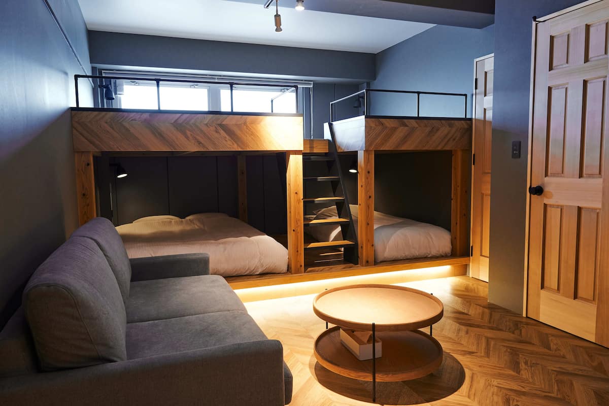 A compact room with bunk beds, a sofa, and a small table.