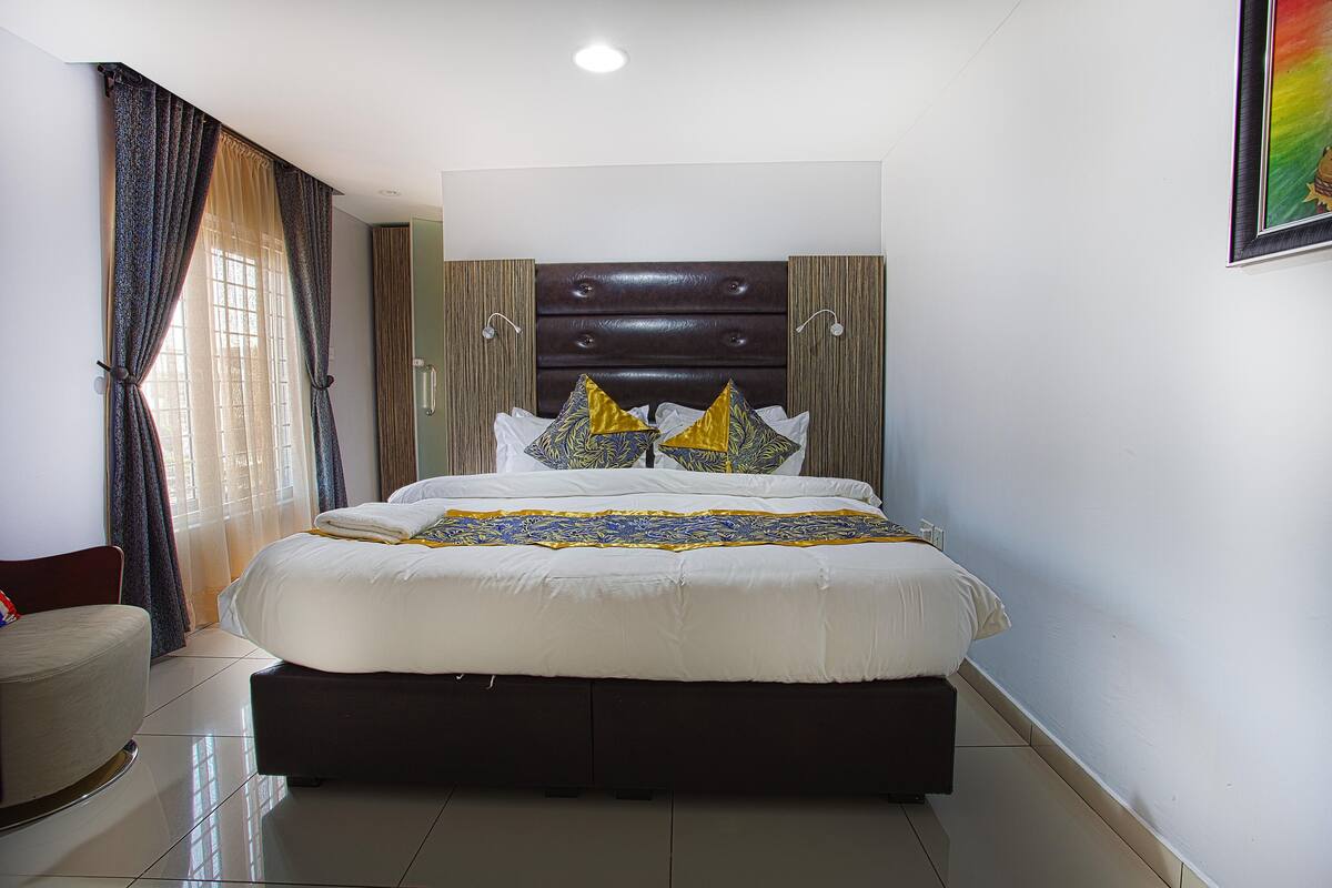 Ein Hotelzimmer mit einem großen Bett, einem Sessel und einem Gemälde an der Wand.