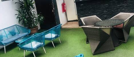 A seating area with blue chairs and a table, a potted plant, and a fire extinguisher.