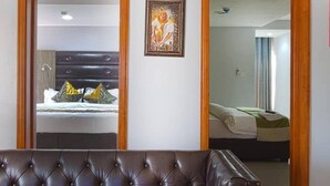 A living room with a brown leather sofa, wooden-framed mirrors, and a framed artwork on the wall. - H21 Apartments & Lounge (Lekki)