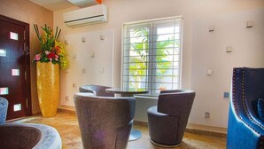 A modern lobby with a seating area, a large vase with flowers, and a window with a view of greenery. - H21 Apartments & Lounge (Lekki)