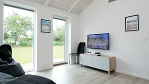 Una sala de estar moderna con un televisor grande, un sofá y una consola minimalista.
