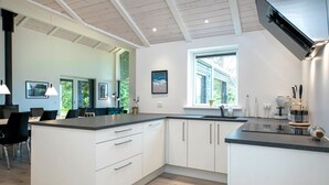 Una cocina moderna con armarios blancos, una isla grande y un ventanal que proporciona luz natural.