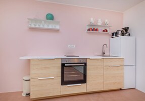 Uma cozinha moderna com forno embutido, armários brancos e frigorífico branco.