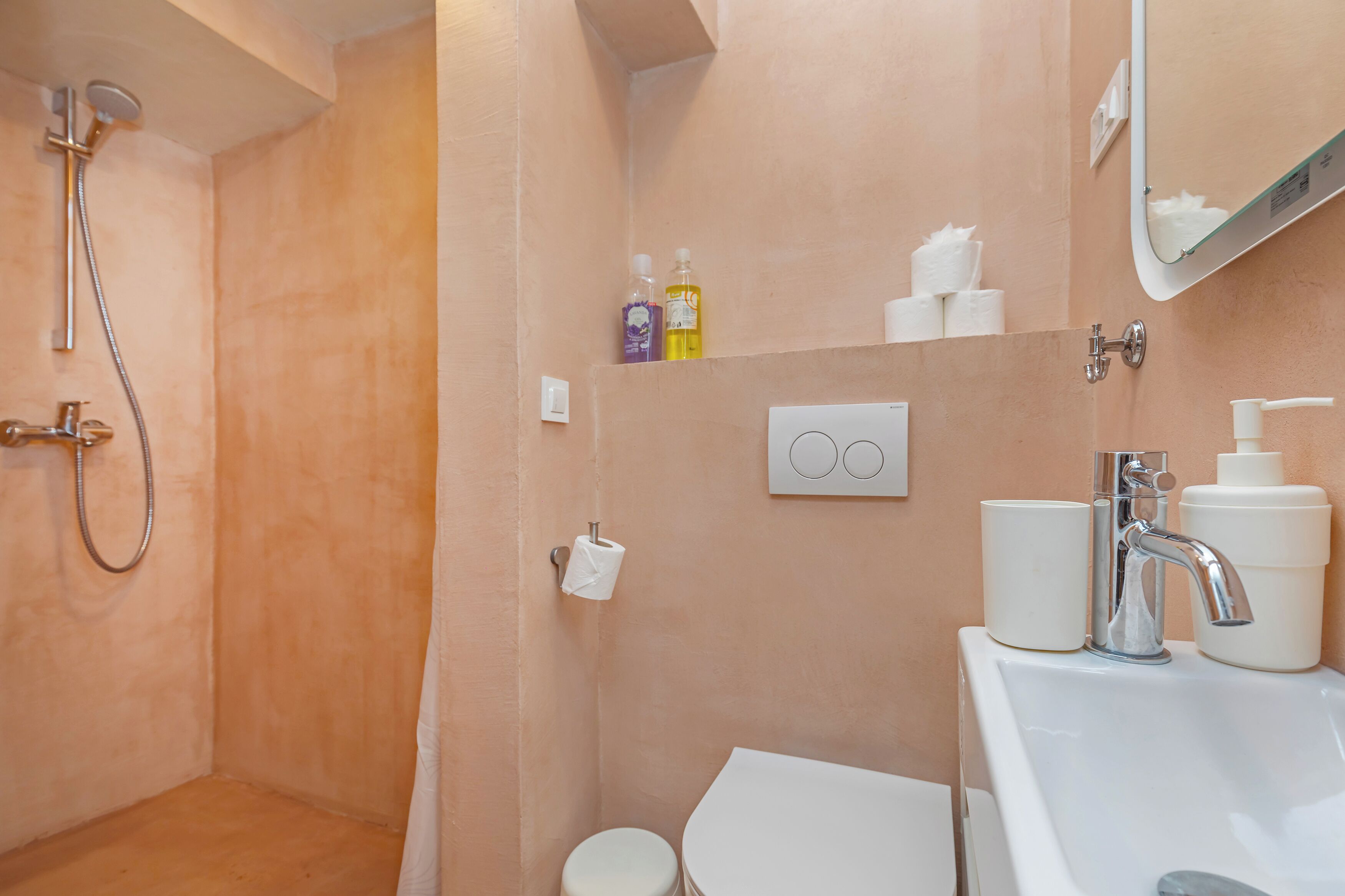 A bathroom with a shower, toilet, sink, and a mirror.