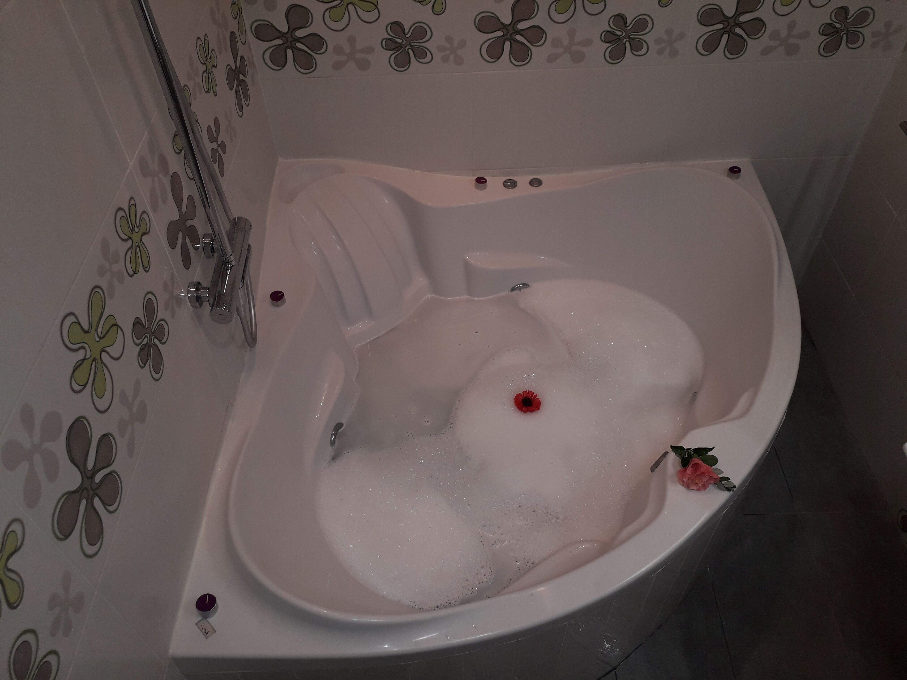 Eine Badewanne mit Schaum, einer Rose und einem Wasserhahn.