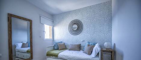 Un dormitorio con cama, espejo, un reloj de pared y ventana.