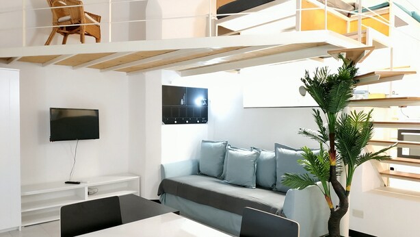 A modern, multi-level living space with a sofa, TV, and dining area. - Holiday Apartment in Genova Fieno (Genoa)