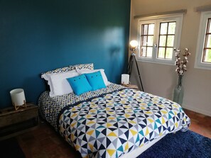 Relax in this serene bedroom with a large bed, blue accent wall, and natural light pouring in through the window.
