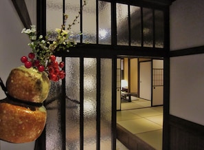 Una habitación japonesa tradicional con suelo de tatami, una mesa baja y una puerta corredera.