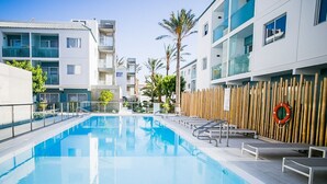A modern hotel with a swimming pool, multiple balconies, and a bamboo fence. - Sunset Apartment (Corralejo Fuerteventura) (Corralejo)