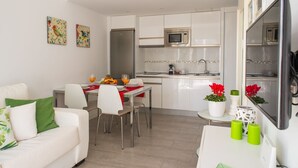 A modern apartment with a dining area, kitchenette, and a living room. - Sunset Apartment (Corralejo Fuerteventura) (Corralejo)