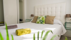 A neatly made bed with a white duvet, two pillows, and a rolled towel. - Sunset Apartment (Corralejo Fuerteventura) (Corralejo)
