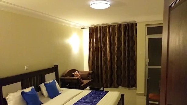 Une chambre d’hôtel avec un lit, une chaise, un rideau et une porte.