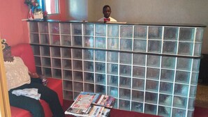 Un espace d’accueil avec une cloison en verre, un canapé rouge et une table avec des magazines.