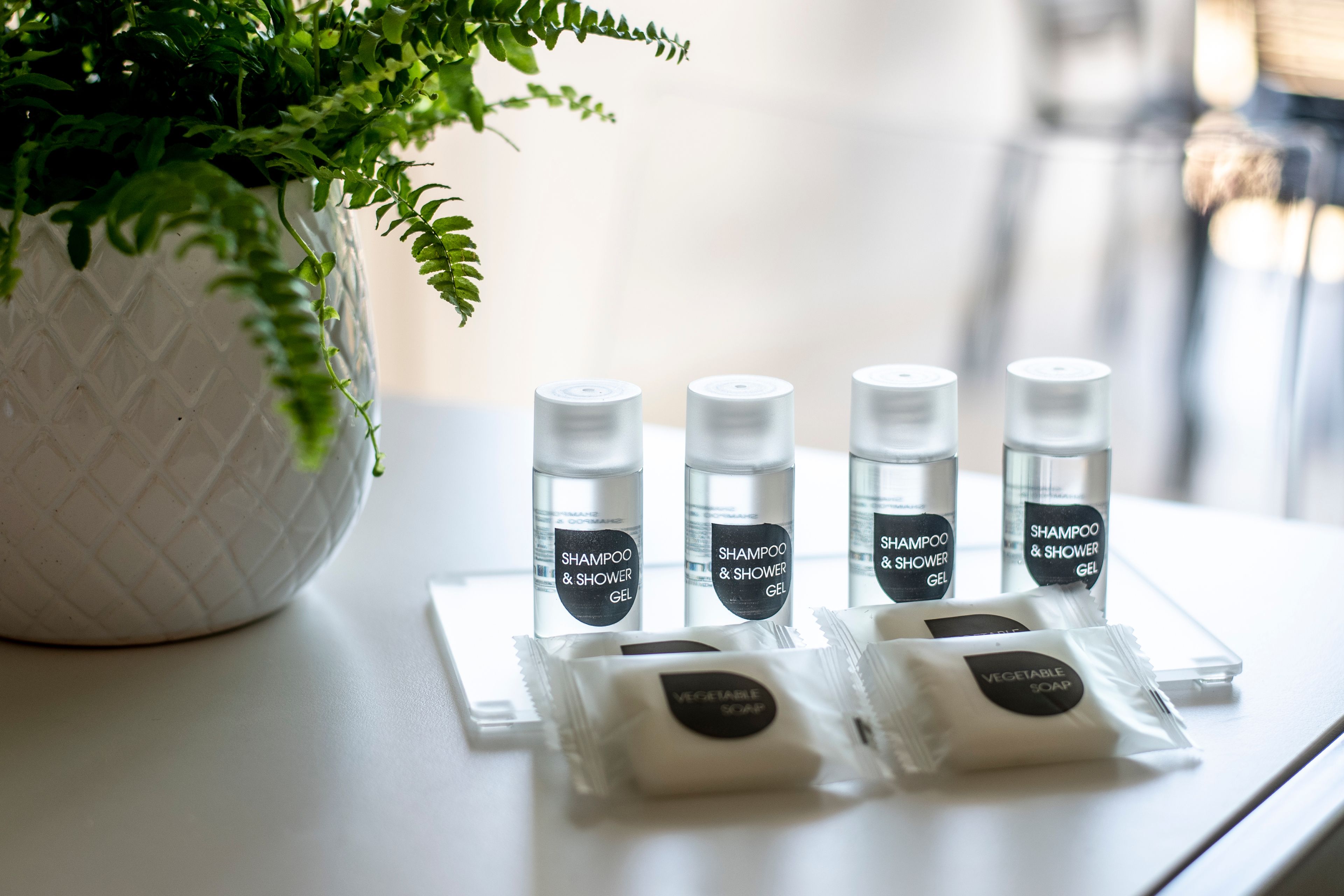 A table with four bottles of shampoo and shower gel, and two packets of vegetable soap.