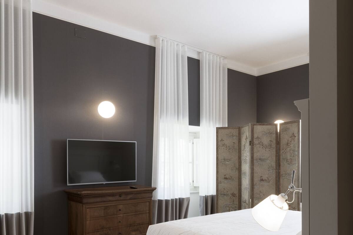 A bedroom with a bed, a dresser, a television, and a bedside lamp.