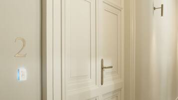 A hallway with a white door, a wall-mounted light fixture, and a number '2' sign.