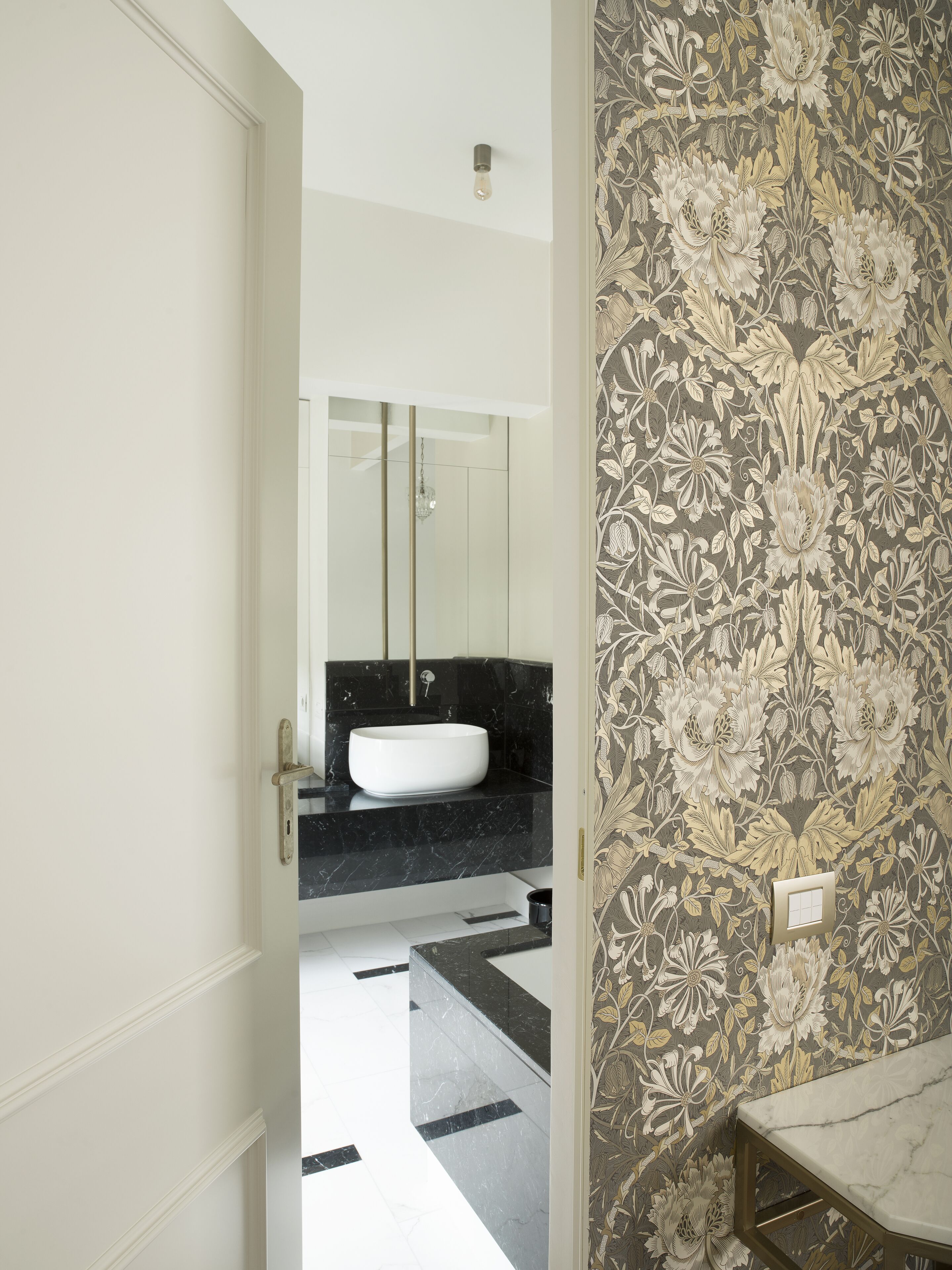 A modern bathroom with a white sink, black marble countertop, and a large mirror.