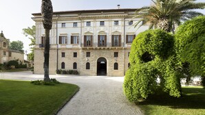 Un edificio histórico con fachada simétrica, una entrada central y un jardín bien cuidado con una palmera.