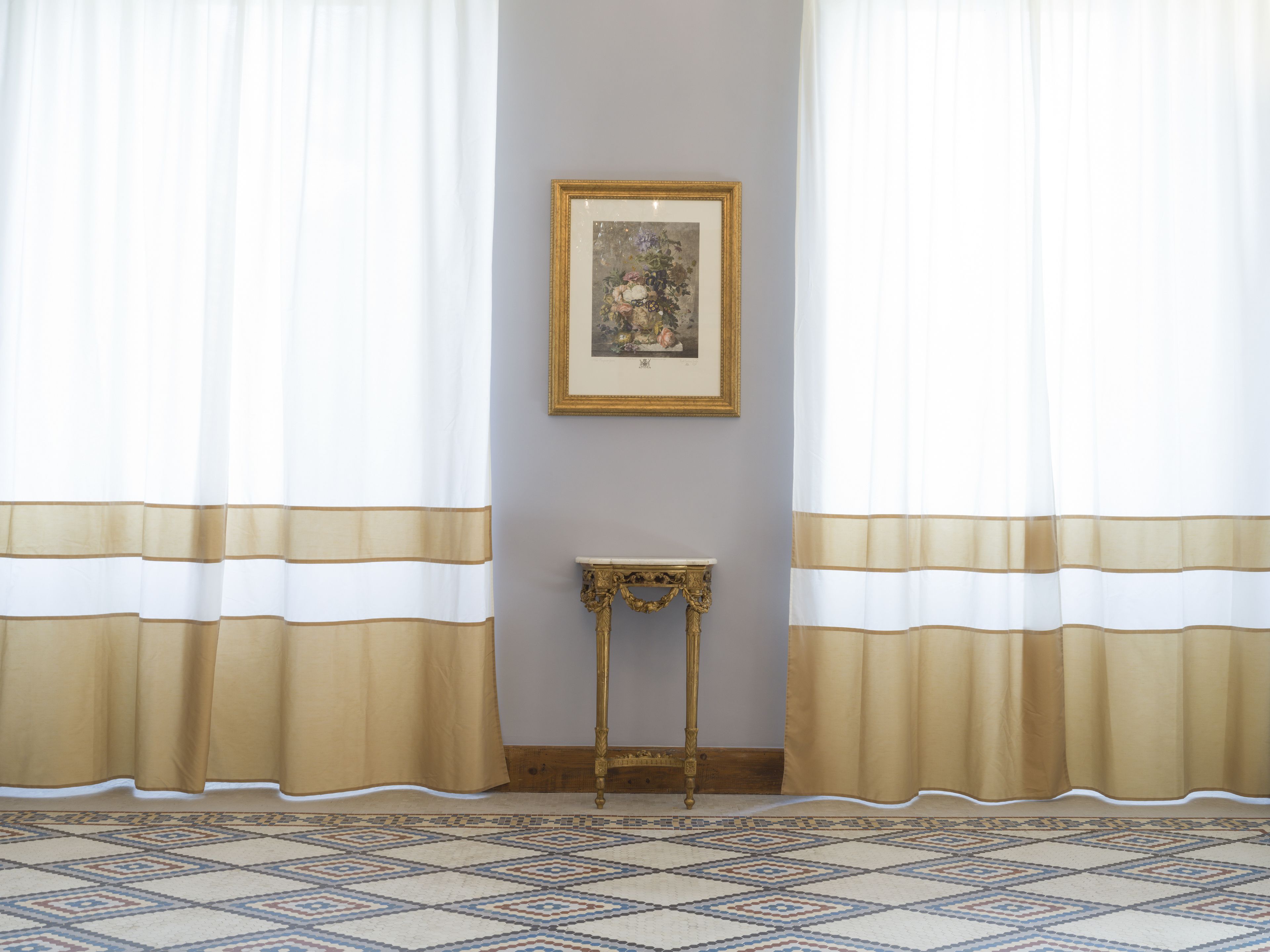 A room with a patterned carpet, a small table, and curtains with horizontal stripes.